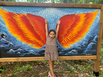 Young girl striking a pose in front of drawn wings.