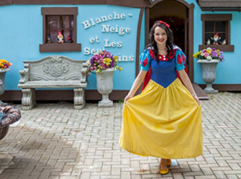 Snow White character in front of a blue house