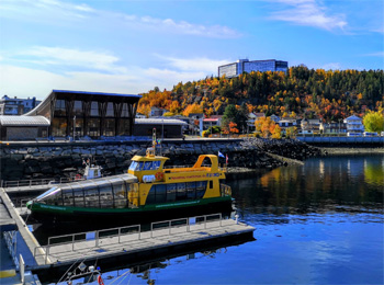 Marina in Saguenay with a small boat and a background of fall foliage.