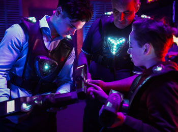 Three people wearing laser tag uniforms in a huddle.