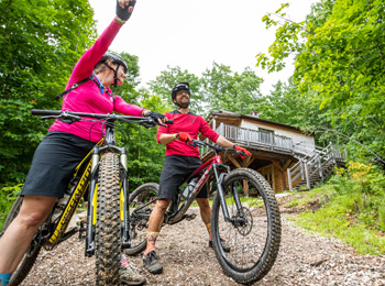 Two mountain bikers in front of a cottage.