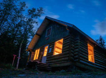 Forest lodge at night lit up from the inside.