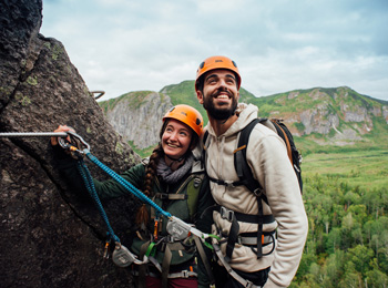 Happy couple on a cliff on a via ferrata trail.