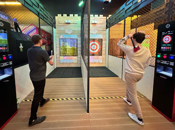 Two men taking part in an axe-throwing activity.