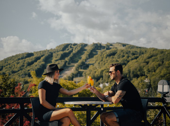 Couple sharing a drink in front of the ski hill in late summer.