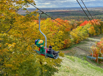 Mascot and boy on a ski lift in the fall.