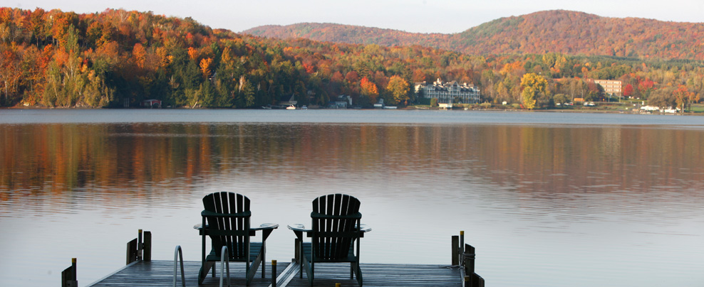 Two patio chairs on a deck in front of Lake Massawippi.