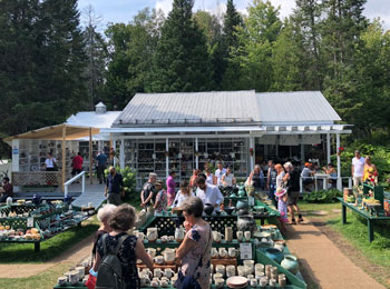 The exhibition site, with a small house and outdoor tables filled with ceramics.