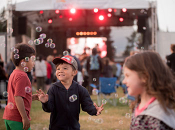 3 kids having fun in front of a stage at the festival.