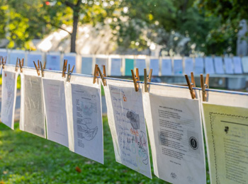 Rope stretched between trees on which papers with poems written on them have been clipped.