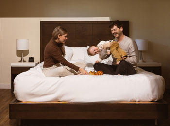 Two young parents and a child on a bed.