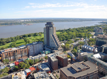 Hotel Le Concorde in Québec City seen from above with the Plains of Abraham and St. Lawrence River in the background.