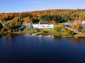 Manoir Lac-Etchemin on the lake with fall-coloured trees behind.