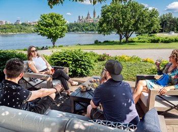 4 friends on patio furniture in front of the Ottawa River.