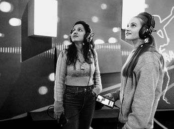 Two young women listening to an audio tour and observing something out of frame.