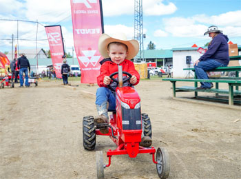 Young boy on a miniature tractor at the Ayer's Cliff Rodeo.