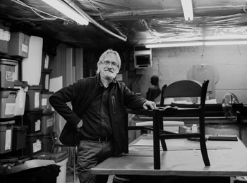 Woodwroking artisan displaying a chair on a workbench.