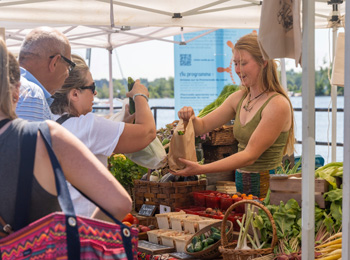 Booth at the farmer's market with customers lined up and merchant.