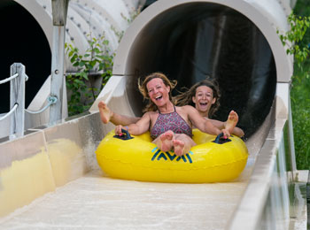 A smiling mother and teenager at the bottom of a water slide.