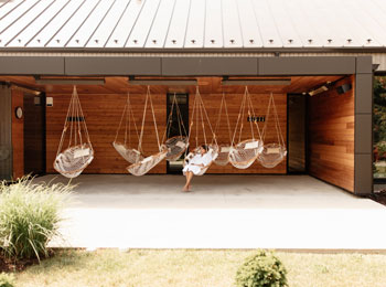 Woman in an outdoor relaxation area, equipped with hanging seats.