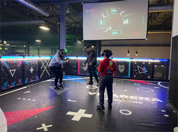 Three people facing off in a virtual reality arena.