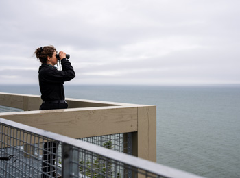 Woman looking at  the sea with binoculars.