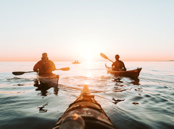 Group of kayakers on the fjord at sunset.