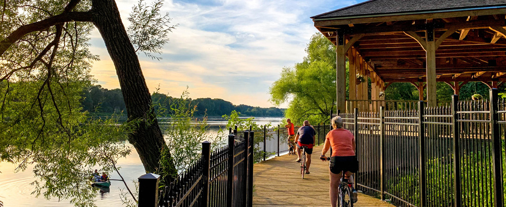 A few cyclists on a waterside bike path.