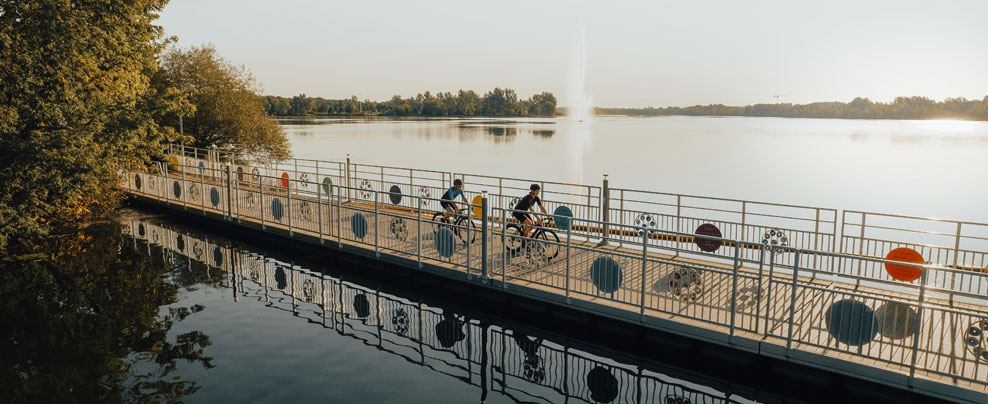 Two cyclists on a bike path over the water.