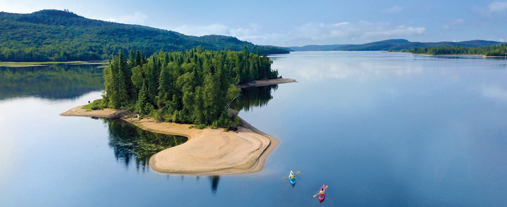 Aerial view of a small island with beach in the middle of a large lake.