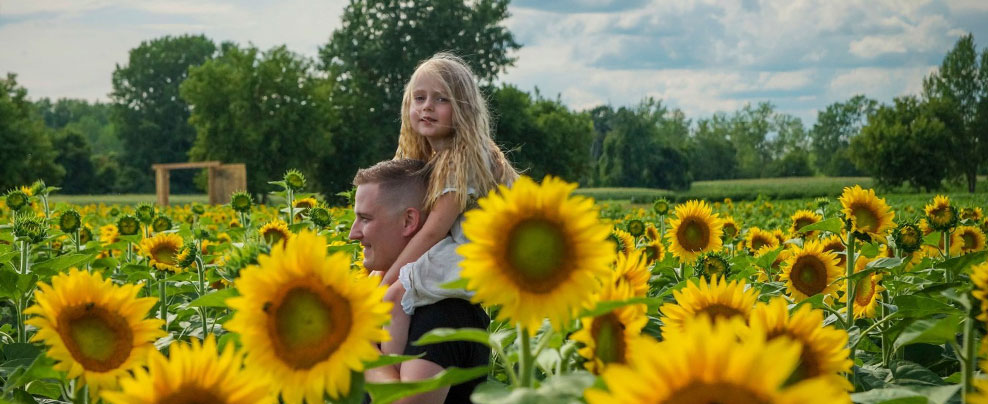 Father and daughter in a field of sunflowers in Laval.