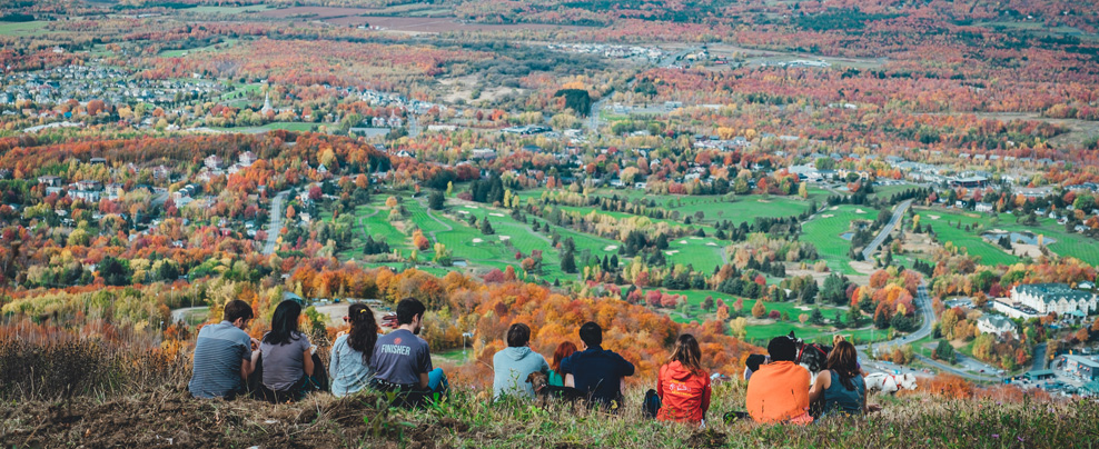 Group of people sitting at the top of a mountain in the fall.