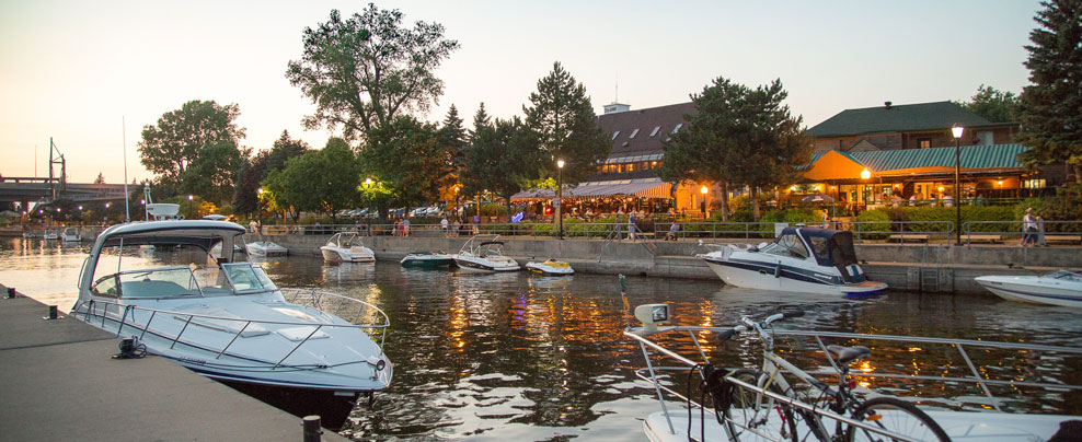 Waterfront with brightly lit shops and docked boats.