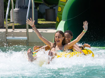 Two happy-looking girls at the bottom of a water slide.